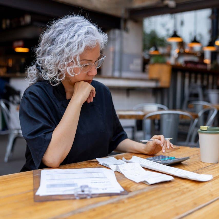Latin American female chef looking worried while doing the accountancy at a restaurant - small business concepts